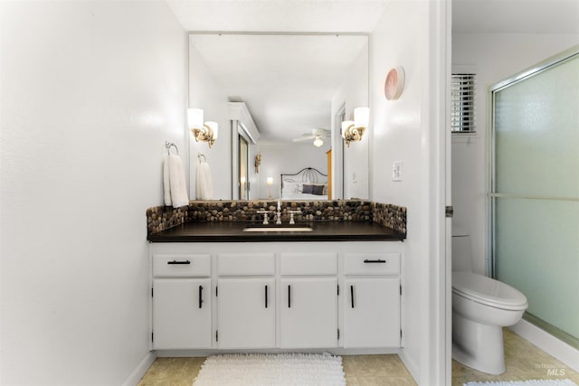 ensuite bathroom featuring vanity, toilet, a ceiling fan, baseboards, and a shower with door