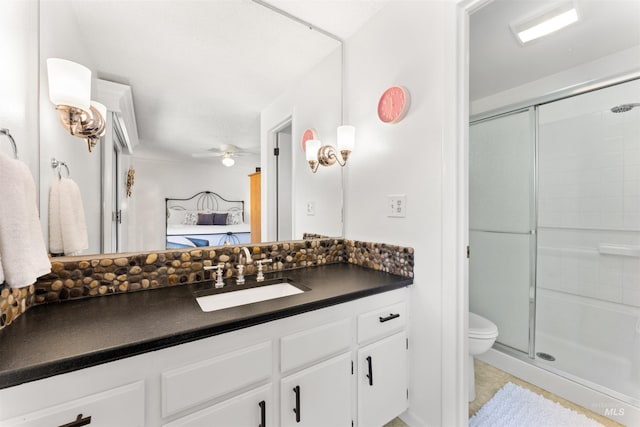 ensuite bathroom featuring ceiling fan, a stall shower, vanity, toilet, and ensuite bath