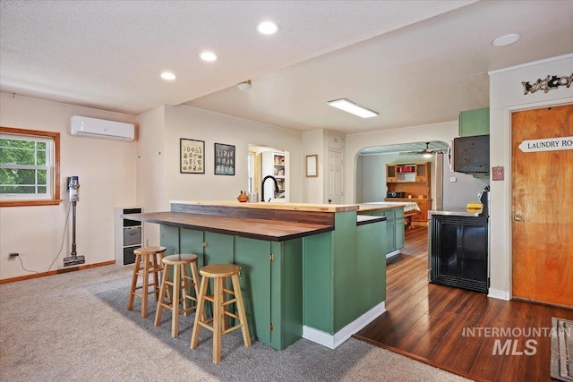 169W 200 N, Jerome, ID 83316 - kitchen featuring green cabinets, a wall mounted air conditioner, a kitchen island with sink, baseboards, and recessed lighting