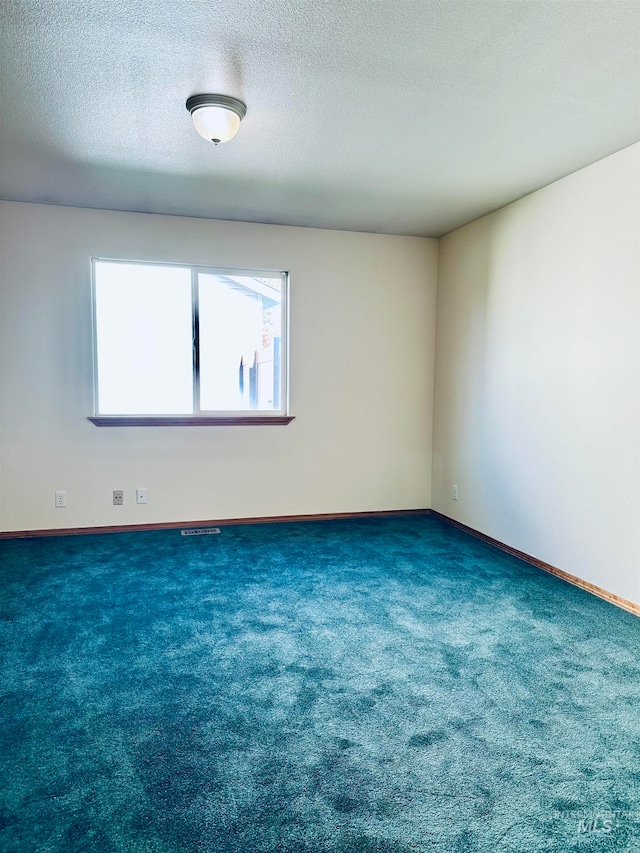 carpeted empty room featuring a textured ceiling