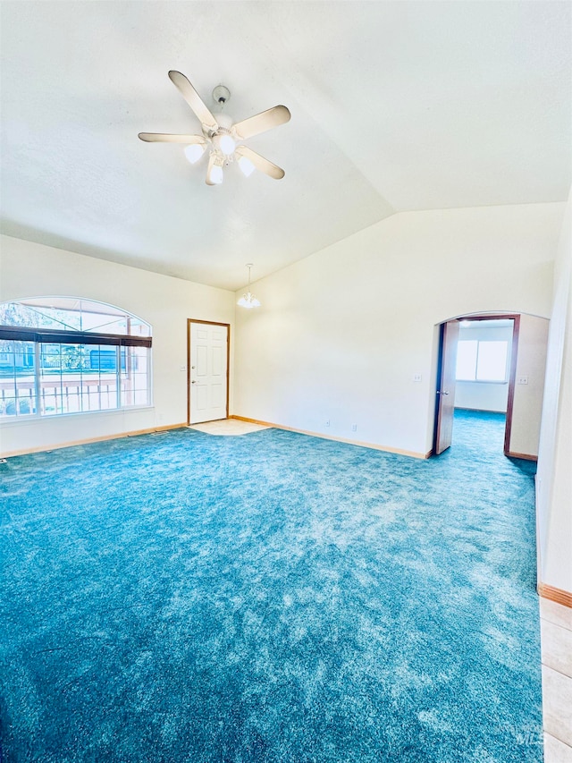 carpeted empty room with ceiling fan with notable chandelier and vaulted ceiling