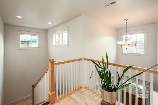 stairway featuring hardwood / wood-style floors and a notable chandelier