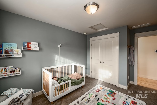 bedroom featuring dark colored carpet, a closet, and a nursery area