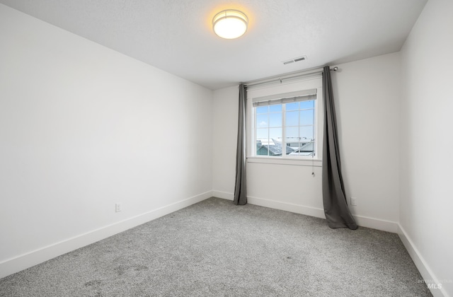 spare room featuring visible vents, carpet flooring, a textured ceiling, and baseboards