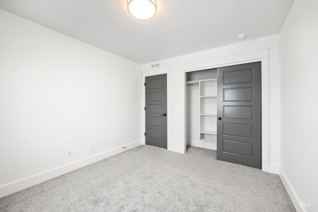 unfurnished bedroom featuring a closet, visible vents, baseboards, and carpet