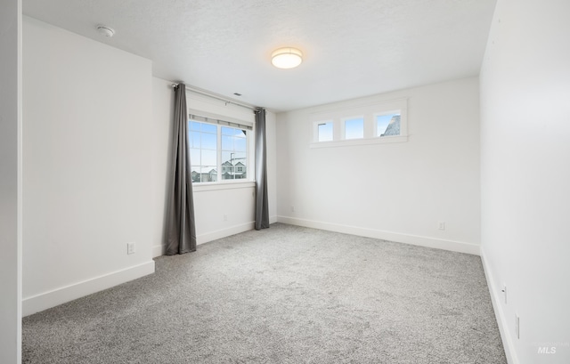 carpeted empty room with a textured ceiling and baseboards