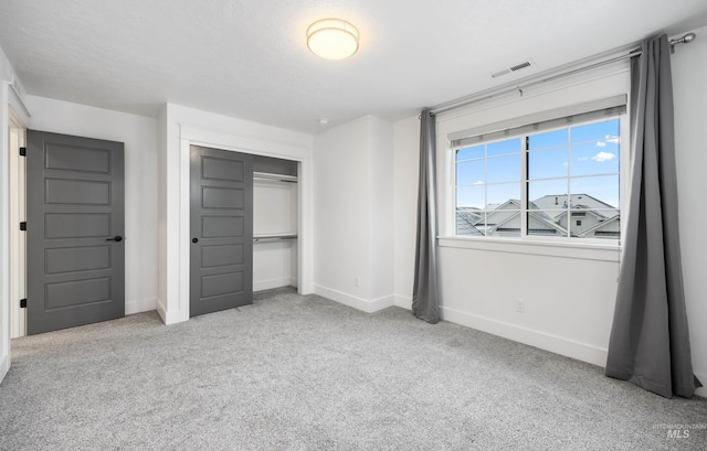 unfurnished bedroom featuring carpet flooring, baseboards, visible vents, and a closet