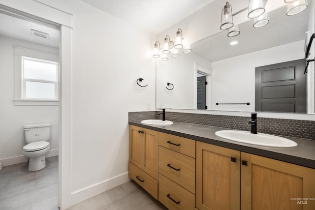 bathroom featuring a sink, visible vents, baseboards, and double vanity