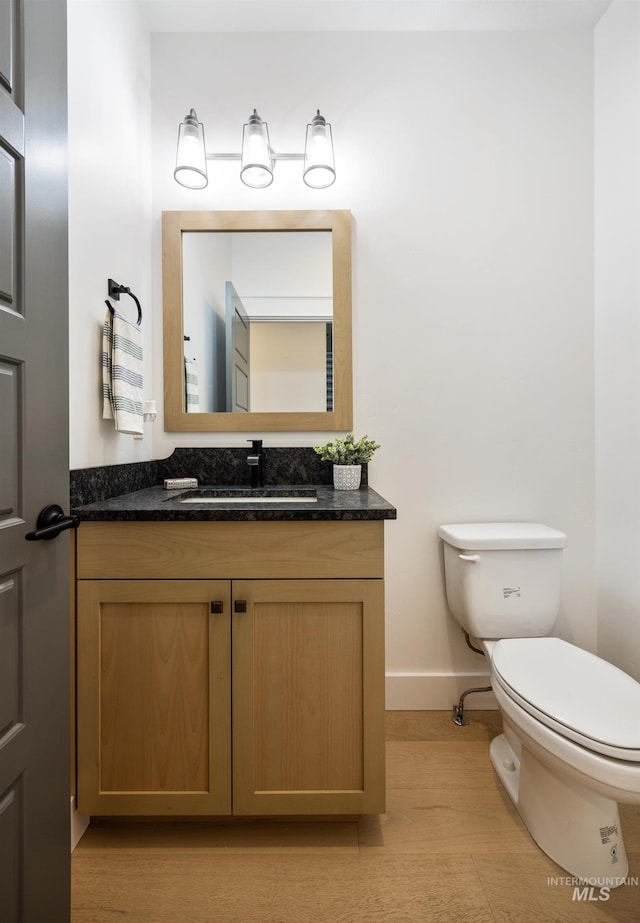 half bathroom with toilet, vanity, and baseboards