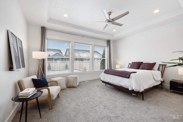 bedroom with a tray ceiling, baseboards, and carpet flooring