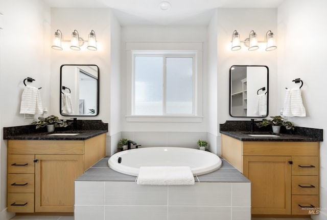 bathroom with tiled bath, a sink, and two vanities