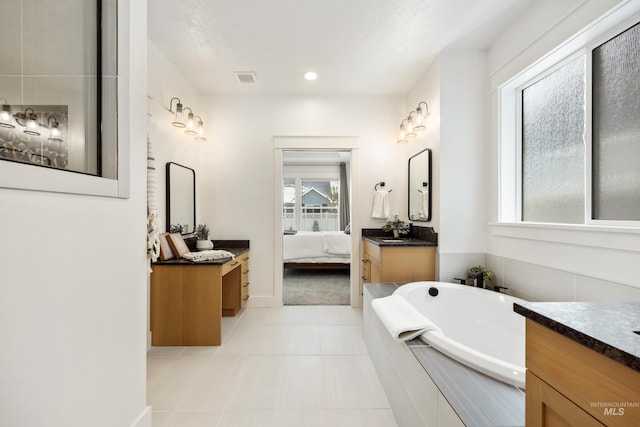 ensuite bathroom with connected bathroom, visible vents, two vanities, tile patterned floors, and a washtub