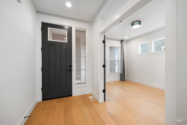 foyer entrance with baseboards, visible vents, a wealth of natural light, and light wood-type flooring