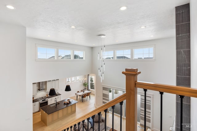 hall with recessed lighting, an upstairs landing, a textured ceiling, and a sink