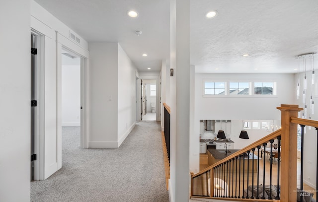 hall featuring visible vents, baseboards, recessed lighting, carpet flooring, and an upstairs landing