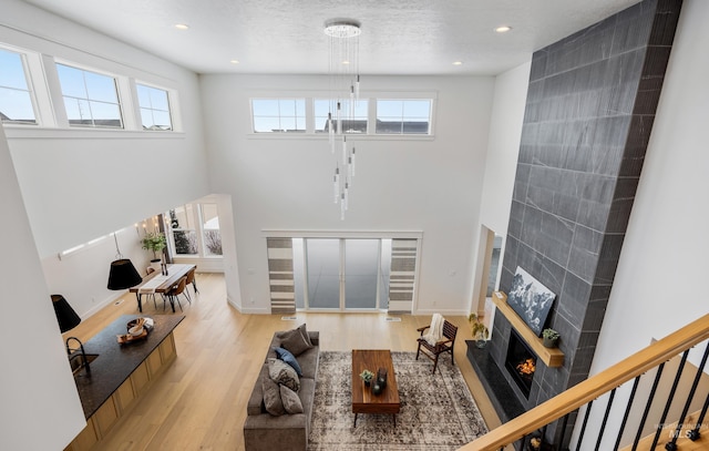 living area featuring an inviting chandelier, a high ceiling, light wood finished floors, and a high end fireplace