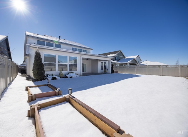 snow covered property featuring ceiling fan and a fenced backyard