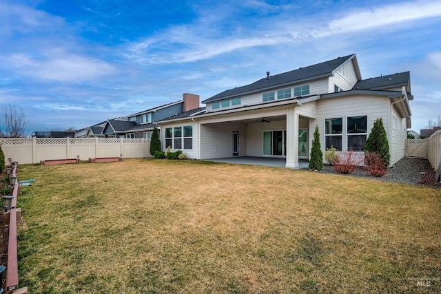 back of property featuring a fenced backyard, a lawn, a ceiling fan, and a patio