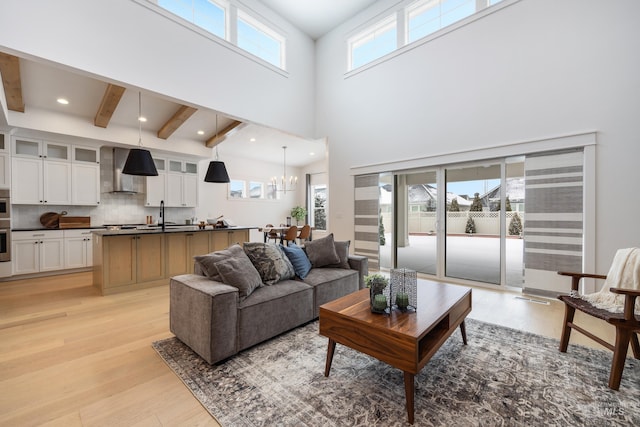 living area featuring a chandelier, beam ceiling, light wood-style flooring, recessed lighting, and a high ceiling