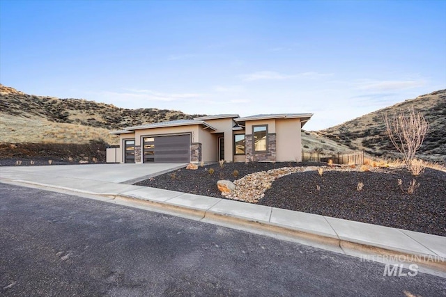 20042 N Swire Green Way Unit 459, Boise, ID 83714 - view of front of home featuring stucco siding, a garage, a mountain view, concrete driveway, and stone siding