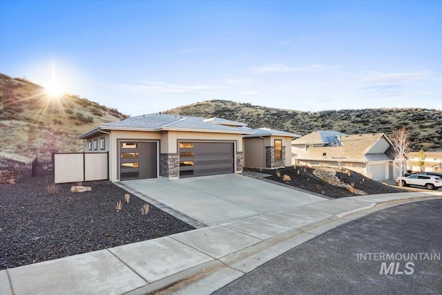 20042 N Swire Green Way Unit 459, Boise, ID 83714 - view of front of house featuring a garage, concrete driveway, a mountain view, stucco siding, and stone siding