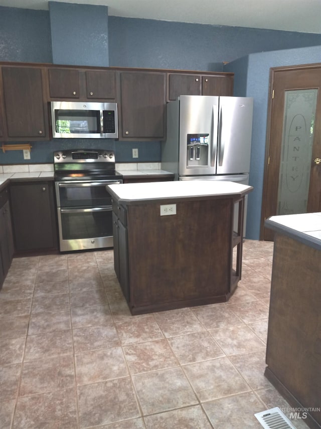 410 Cedar St, Middleton, ID 83644 - kitchen featuring appliances with stainless steel finishes, dark brown cabinets, light countertops, and a kitchen island