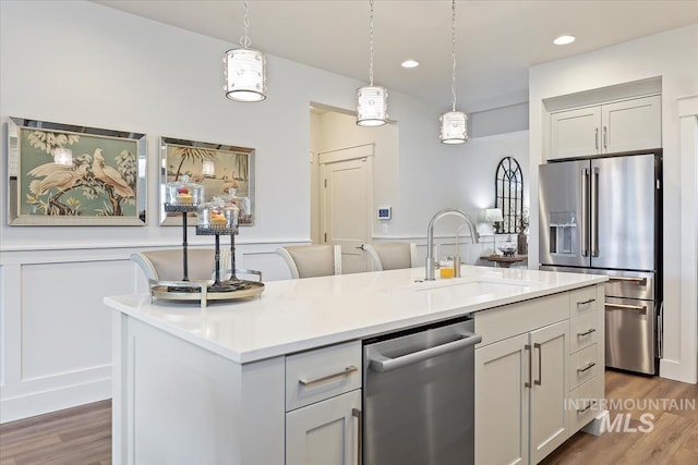 kitchen featuring hanging light fixtures, appliances with stainless steel finishes, light countertops, and a sink