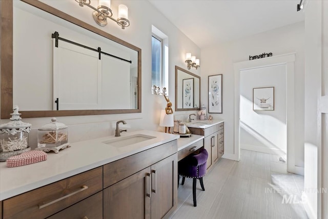 full bathroom featuring two vanities, baseboards, and a sink