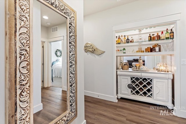 bar with a dry bar, visible vents, dark wood-style flooring, and baseboards