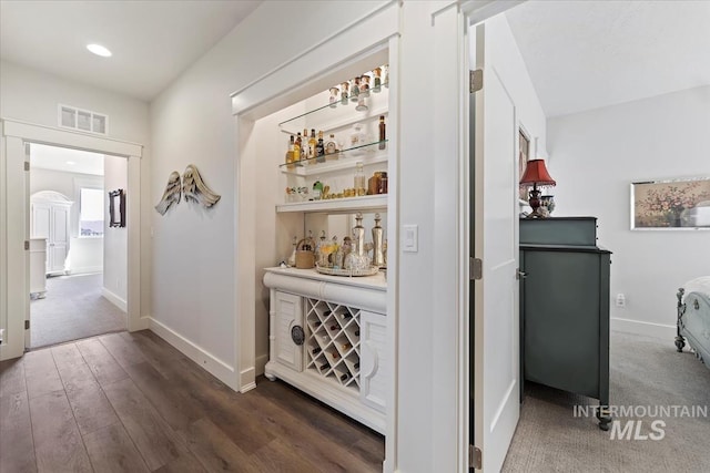 hallway featuring dark wood-type flooring, baseboards, and visible vents