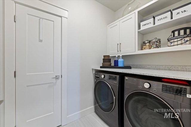 washroom with washer and dryer, cabinet space, and baseboards