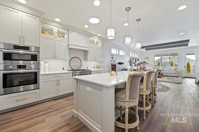 kitchen with light wood-type flooring, a sink, tasteful backsplash, appliances with stainless steel finishes, and light countertops