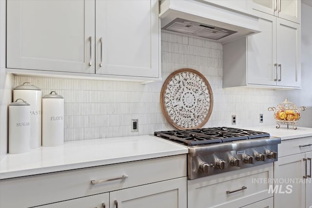 kitchen with backsplash, stainless steel gas cooktop, light countertops, custom range hood, and white cabinets