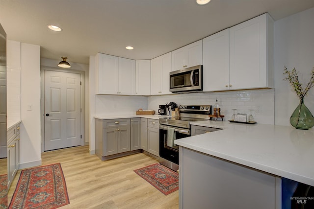 8561 W Goddard, Boise, ID 83704 - kitchen with light countertops, light wood finished floors, gray cabinetry, stainless steel appliances, and decorative backsplash