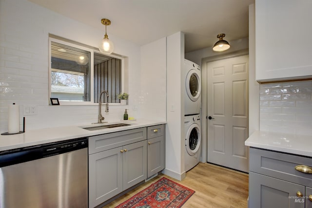 8561 W Goddard, Boise, ID 83704 - washroom featuring stacked washer and clothes dryer, a sink, laundry area, and light wood-type flooring