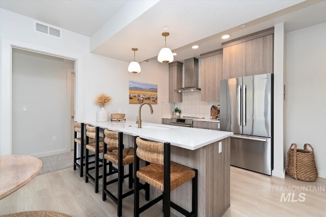 4184 E Haystack St Unit 206, Boise, ID 83716 - kitchen with appliances with stainless steel finishes, wall chimney range hood, a kitchen bar, a sink, and light wood-type flooring