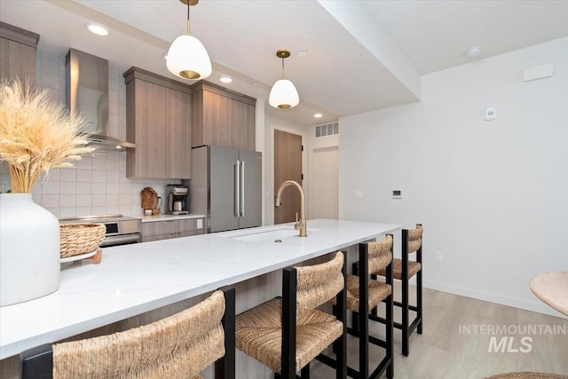 4184 E Haystack St Unit 206, Boise, ID 83716 - kitchen with appliances with stainless steel finishes, wall chimney exhaust hood, a sink, a kitchen breakfast bar, and light wood-style flooring