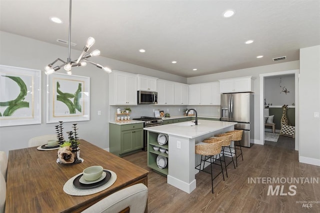 5591 W Aralia Dr, Meridian, ID 83646 - kitchen with a kitchen breakfast bar, white cabinets, recessed lighting, visible vents, and appliances with stainless steel finishes