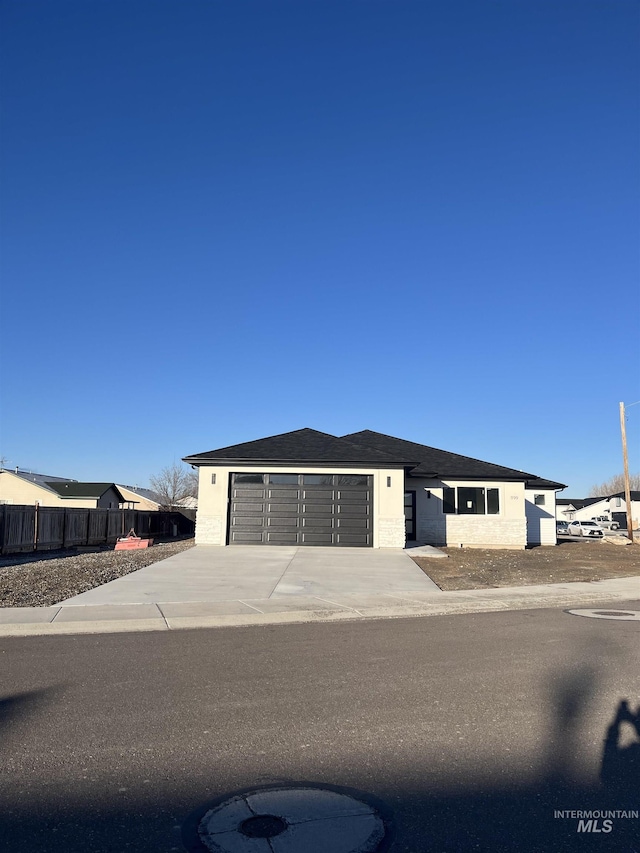 view of front of property featuring a garage, driveway, and fence