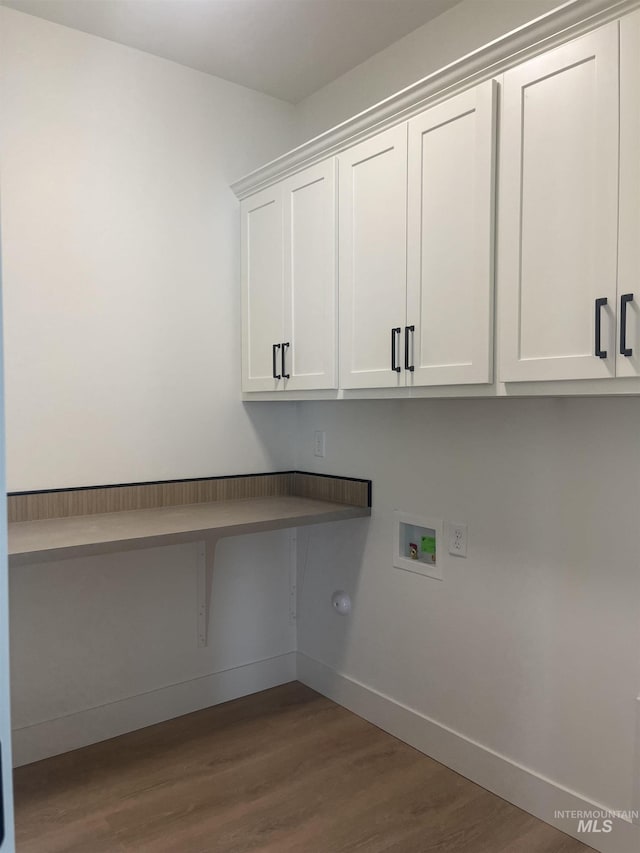 washroom with cabinet space, hookup for a washing machine, baseboards, and wood finished floors