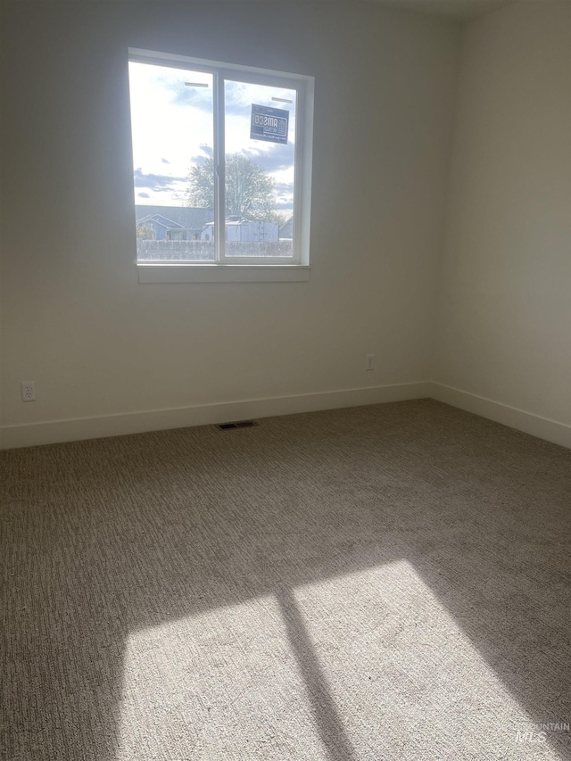 empty room featuring light carpet, baseboards, and visible vents