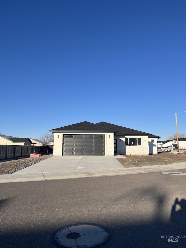 view of front of property with concrete driveway, roof with shingles, fence, and an attached garage