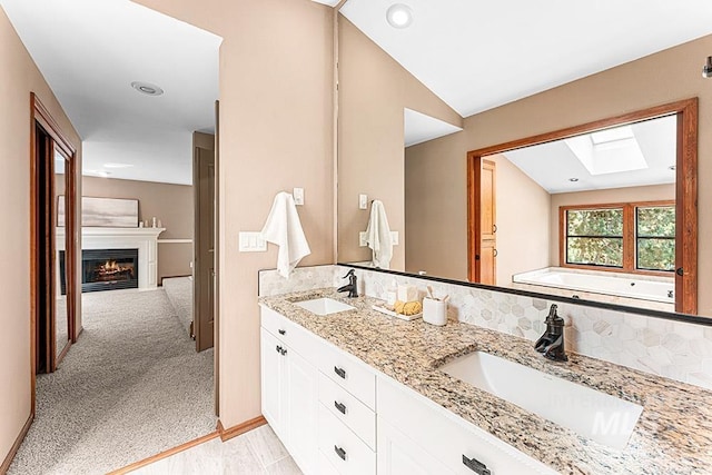 9817 W Gurdon Ct, Boise, ID 83704 - full bathroom featuring a skylight, double vanity, a lit fireplace, and a bath