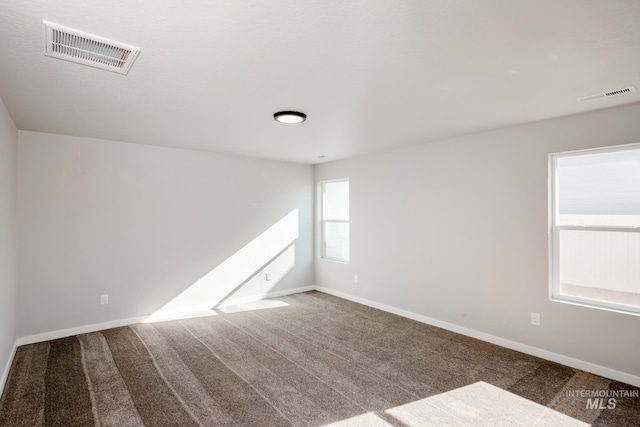 spare room featuring carpet, visible vents, and baseboards