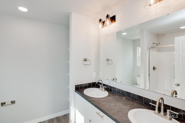 full bathroom with a shower, a sink, toilet, and baseboards