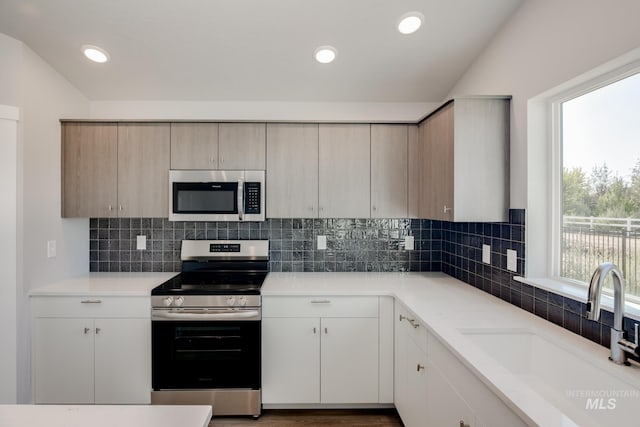 kitchen featuring stainless steel appliances, recessed lighting, light countertops, backsplash, and a sink