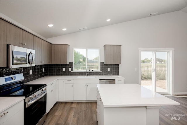 kitchen with lofted ceiling, stainless steel appliances, light countertops, and a center island