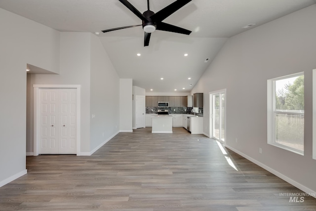 unfurnished living room featuring ceiling fan, high vaulted ceiling, recessed lighting, baseboards, and light wood-style floors