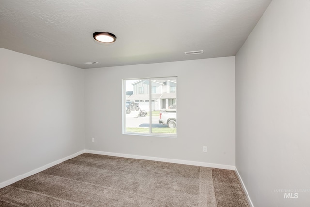 carpeted empty room with visible vents, a textured ceiling, and baseboards