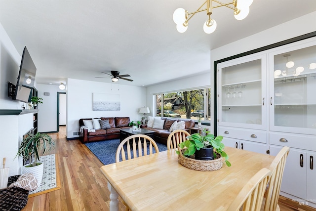 1706 Hervey, Boise, ID 83705 - dining room featuring light wood finished floors, a fireplace, and ceiling fan with notable chandelier